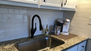 A kitchen with a granite countertop, a stainless steel sink, white cabinets, a coffee maker, and a bottle of hand soap. - Capital City Condo #1 close to Interstate, Water Park, Restaurants and Shopping (Frankfort)