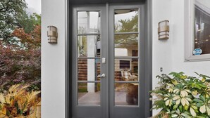 A modern building entrance with a double door, a small porch, and a potted plant.
