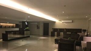 A modern living area with a kitchen, a seating area with sofas, and a reception desk. - Happy Place at Trees Residences Fairview (Quezon City)