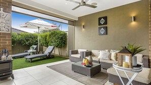 A modern outdoor living area with a patio, lounge chairs, a sofa set, and a dining table.