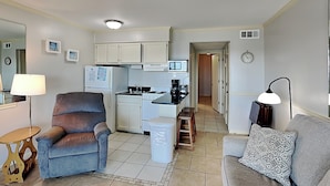 A compact living space with a kitchenette, a sofa, a chair, and a small table. - Cozy oceanfront condo w. community pool + beach access. (Tybee Island)