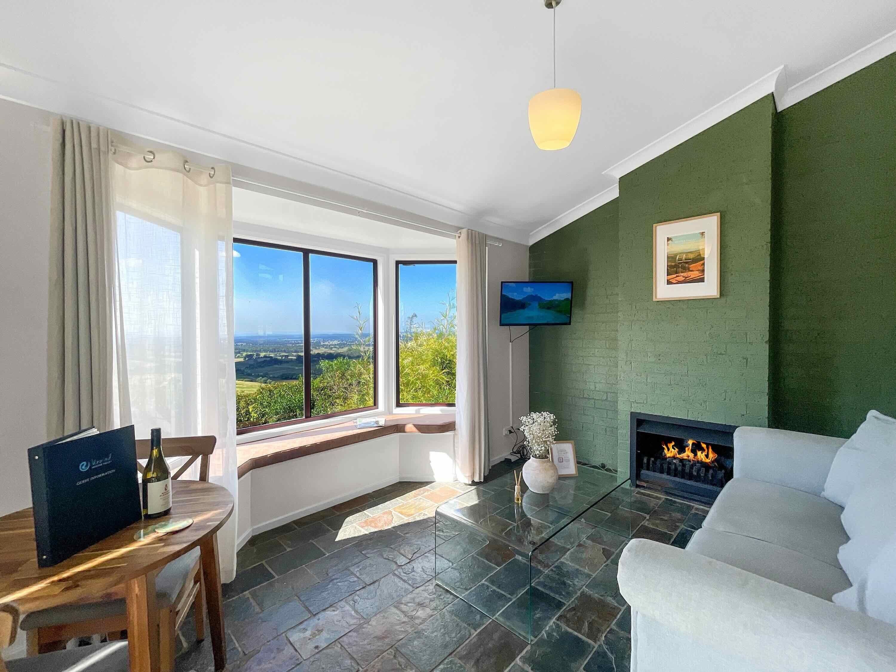 A modern living room with a fireplace, a television, and a large window offering a scenic view.