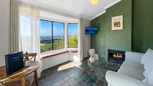 A modern living room with a fireplace, a television, and a large window offering a scenic view. - Villa 3 @ Bimbadeen Estate - Split level villa with views that stretch on forever - just for 2! (Mount View)