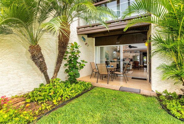 Una casa moderna con un patio, un comedor con sillas y una mesa, y una cocina a la vista.