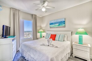 A hotel room with a bed, a ceiling fan, a TV, a window with curtains, a painting, and two bedside lamps. - *Wonderful Views!* Gulf Front! Aug 15 - 19th open! (Panama City Beach)