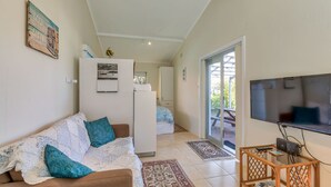 A cozy living room with a sofa, a television, and a refrigerator. - Riverside Studio, Minnamurra, South Coast (Minnamurra)