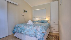 A bedroom with a bed, a nightstand, a dresser, and a window with a view. - Riverside Studio, Minnamurra, South Coast (Minnamurra)