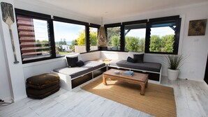 A cozy corner with a built-in bench, a coffee table, and a view of the outdoors. - The Werri Shack, Gerringong (Gerringong)