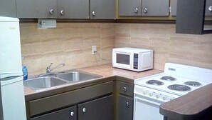 A compact kitchen with a sink, a microwave, and a stove.