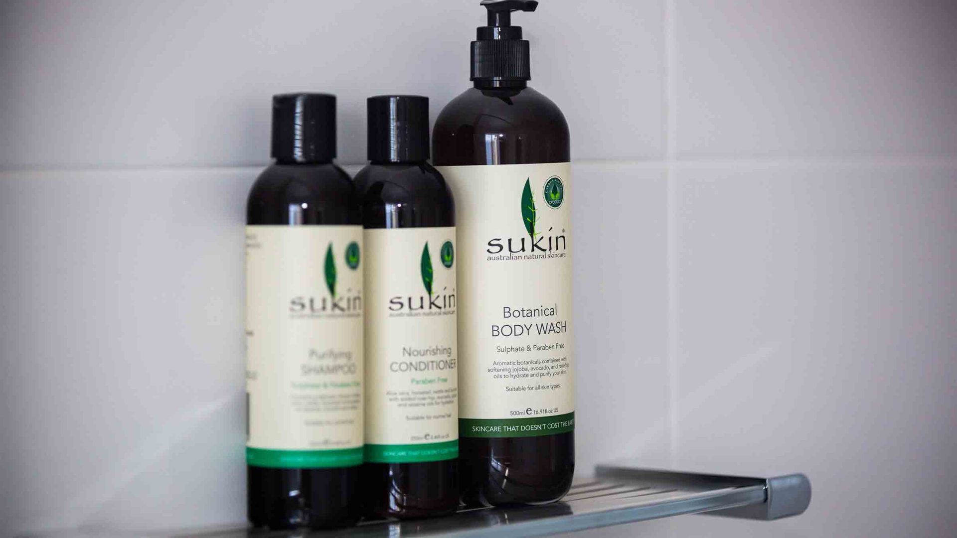 Tres botellas de Sukun gel de ducha en una estantería.