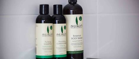 Tres botellas de Sukun gel de ducha en una estantería.