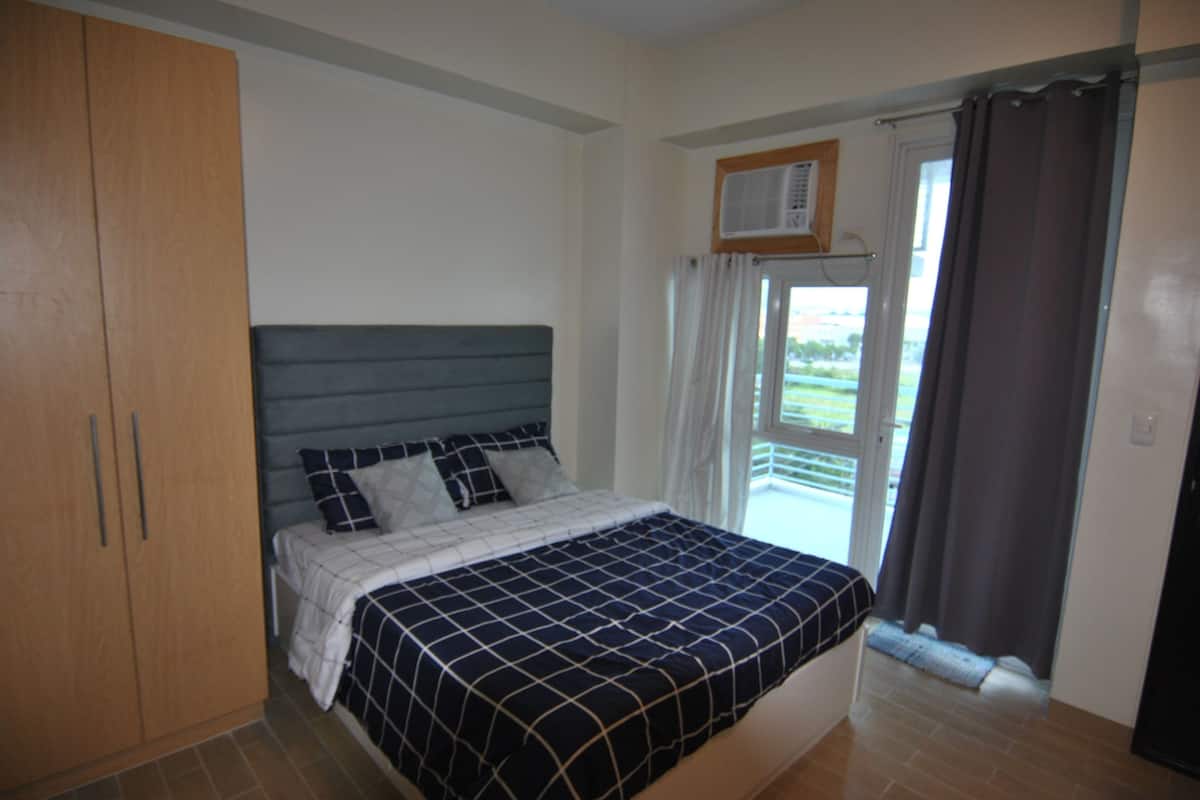 Quarto com cama, guarda-roupa e janela com cortinas.