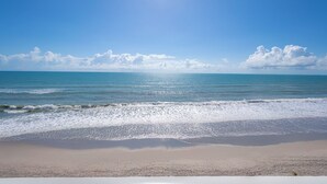 Ein Strand mit blauem Himmel und ruhigem Wasser.