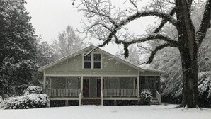 Uma cabana de madeira com varanda, rodeada por árvores cobertas de neve.