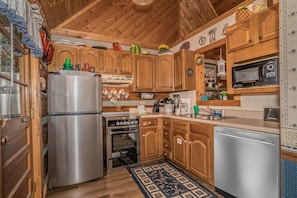 Una cucina in legno con elettrodomestici in acciaio inossidabile, pensili in legno e un tappeto a motivi.