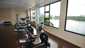Une salle de sport équipée de matériel d’exercice et dotée de grandes fenêtres donnant sur un plan d’eau.