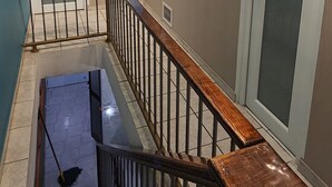 Una escalera con barandillas y pasamanos de madera que conduce a un rellano con una puerta y un cuadro colgado en la pared.