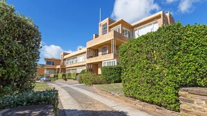 A multi-story residential building with a brick facade, multiple balconies, and a well-maintained garden area. - BEACH BELLE - MORNINGTON (MORNINGTON)