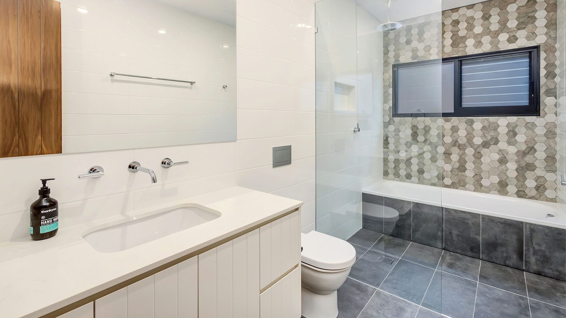 A modern bathroom with a white sink, a toilet, and a shower area.