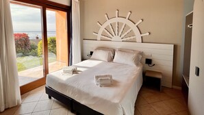 A bedroom with a large bed, a sun-shaped wall decoration, and a view of the outdoors.