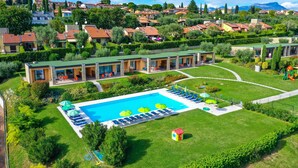A hotel with a swimming pool, sun loungers, and a well-maintained garden.