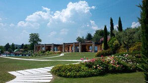A hotel with a garden pathway leading to the entrance, surrounded by lush greenery and flowering plants.