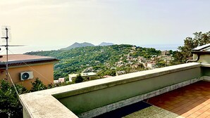 Una terraza en la azotea con vistas a una colina verde y montañas distantes.