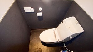 Un baño moderno con un inodoro, un par de zapatos y un rollo de papel higiénico en el suelo.