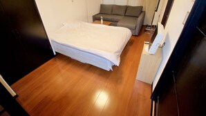Un dormitorio con una cama, un sofá, una mesita de noche y una lámpara.