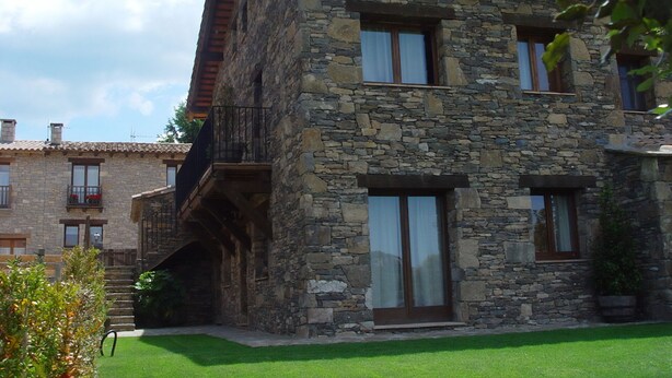A stone building with a balcony, large windows, and a well-maintained lawn. - Rural apartment L'Alzina for 2 people (Tavertet)