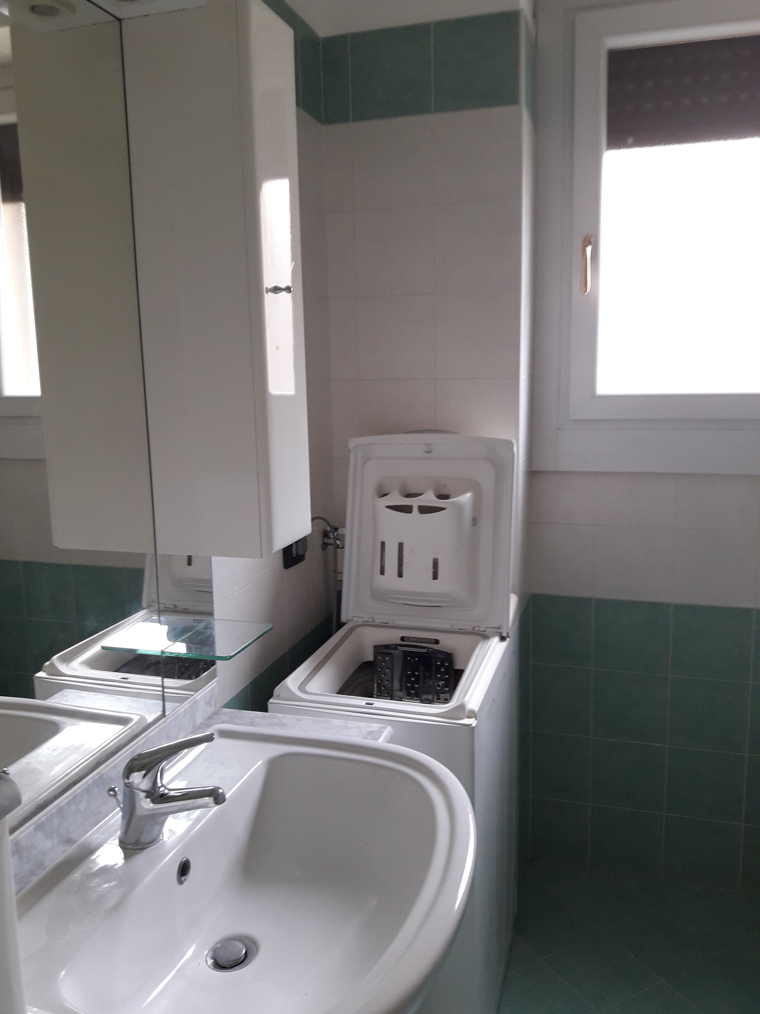 Une salle de bain avec un lavabo blanc, une cloison en verre et des toilettes avec un abattant blanc.