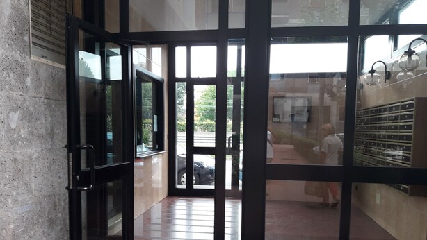 A lobby with a glass door leading outside, a tiled floor, and a wall-mounted light fixture. - San Raffaele Città Studi Politecnico CIN IT015146C2F3B9XNN (Milano)