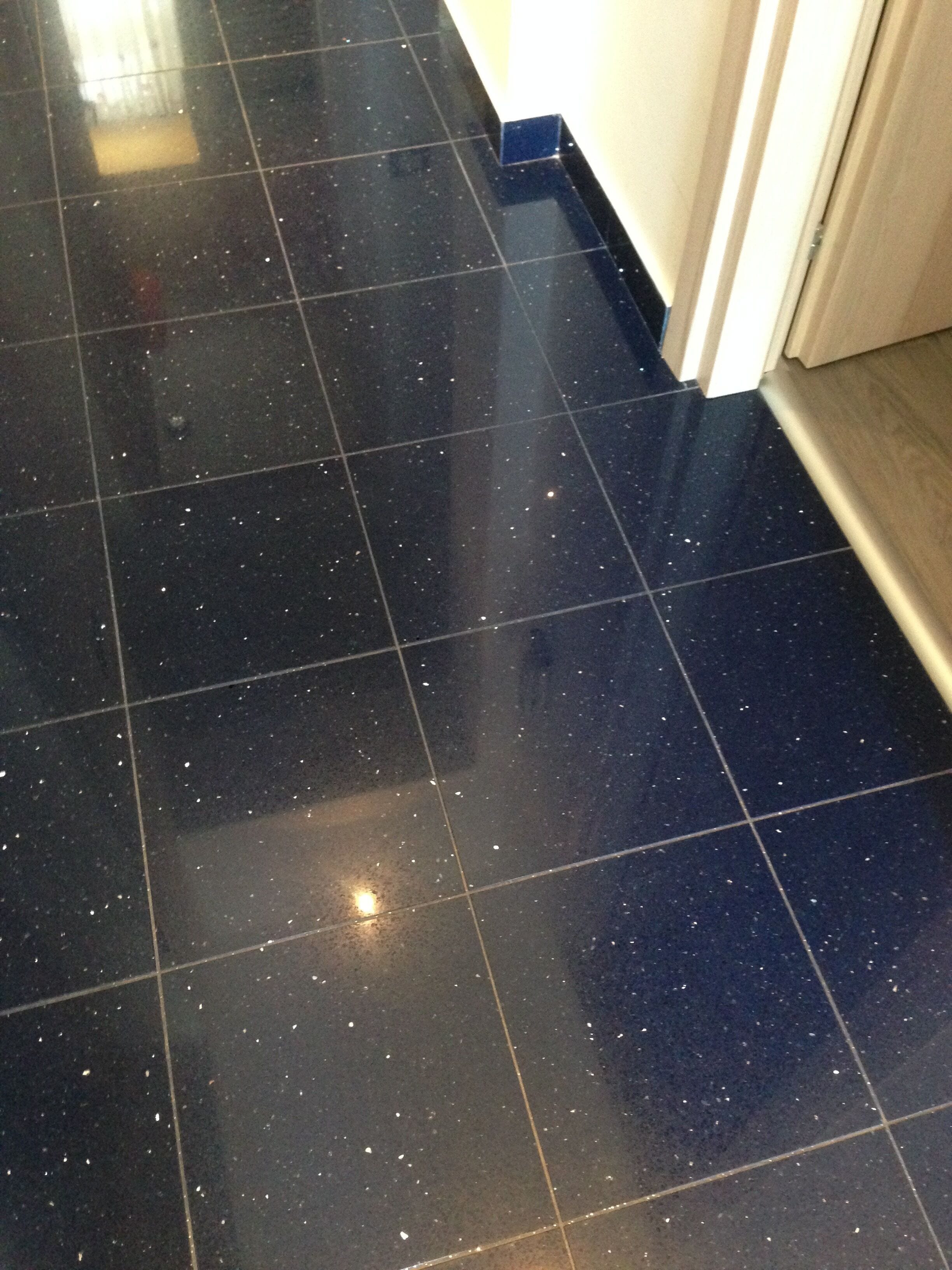 Un couloir doté d’un sol carrelé de carreaux noirs et d’un cadre de porte en bois.
