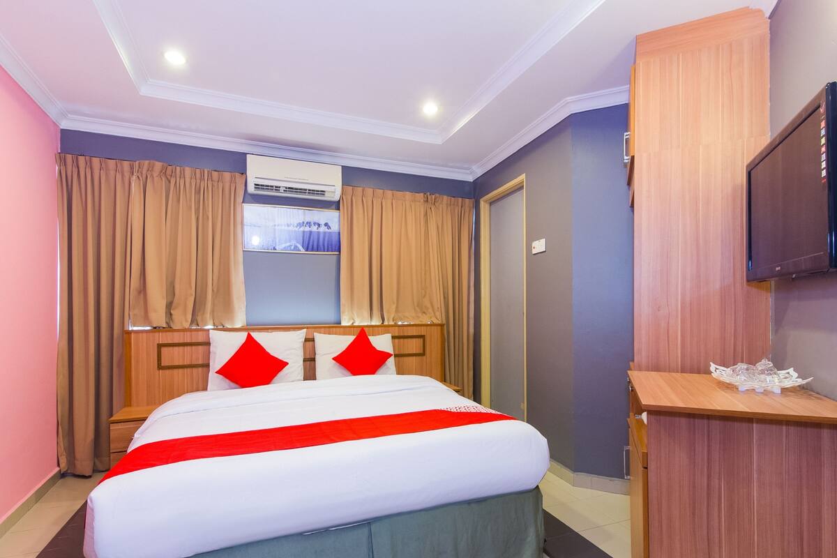 A hotel room with a bed, curtains, a television, and a window with a view.