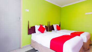 A hotel room with two beds, green walls, and a white door.
