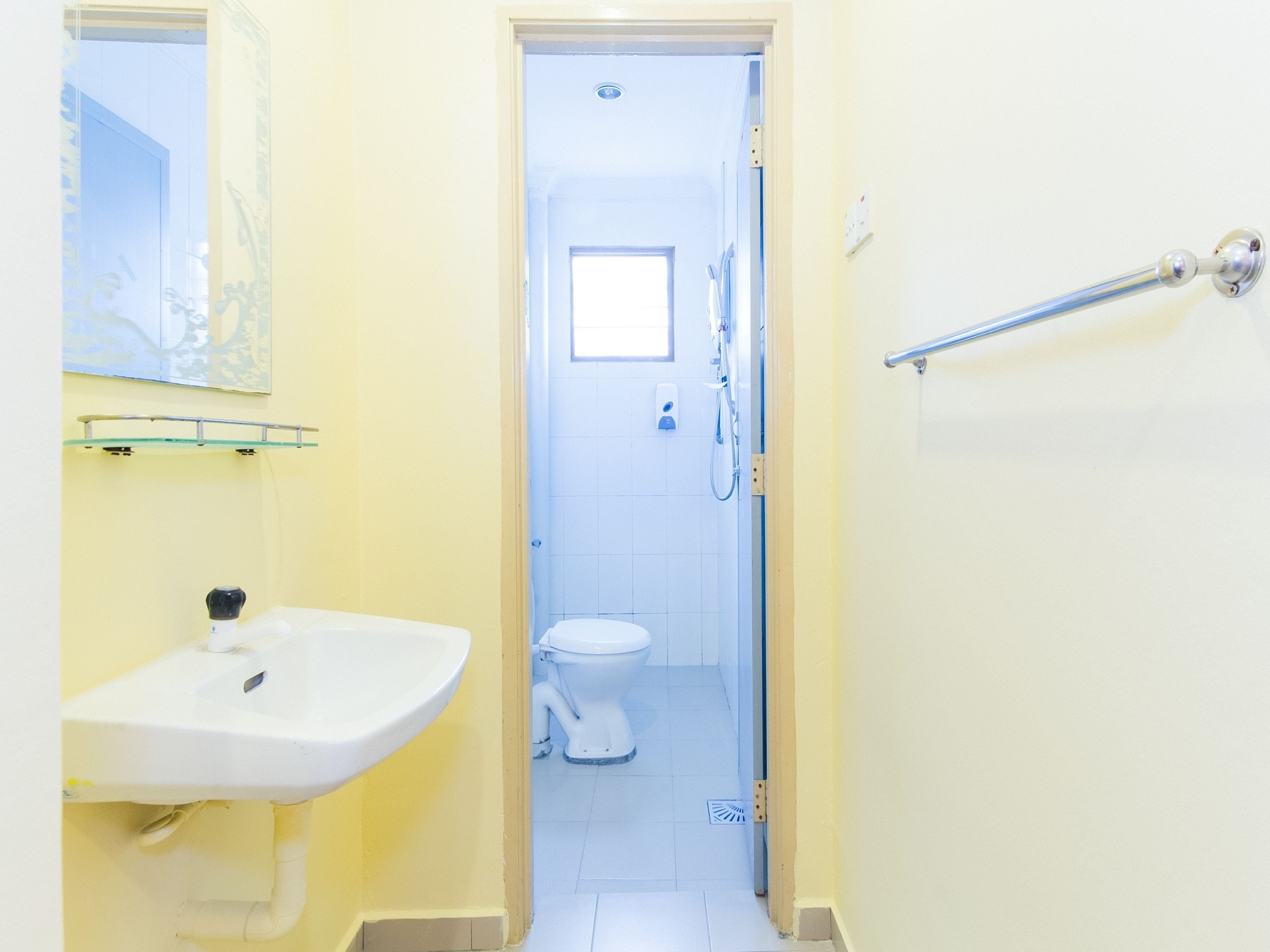 A narrow bathroom with a white sink, a mirror, and a toilet.