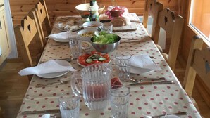 Una mesa de comedor de madera dispuesta con platos, cubiertos, vasos y una variedad de alimentos.
