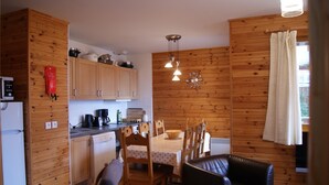 Cocina compacta con armarios de madera, una mesa de comedor con sillas y un sofá de cuero negro.