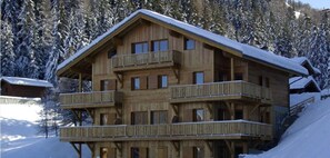 Eine Holzhütte mit mehreren Balkonen, umgeben von schneebedeckten Bäumen.