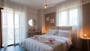 Una habitación de hotel con una cama grande, un espejo redondo, una mesita pequeña y un balcón con vistas.
