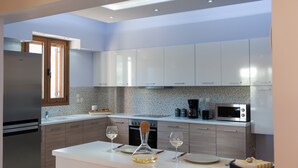 Una cocina moderna con electrodomésticos de acero inoxidable, armarios blancos y una barra desayunadora.