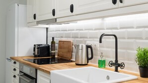 A modern kitchen with white cabinets, a wooden countertop, a sink, a stove, and a refrigerator. - UPSTREET Desirable 1BD Apt in Kolonaki (Athens)