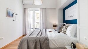 A bedroom with a bed, bedside table, lamp, and a wall with a framed quote. - UPSTREET Desirable 1BD Apt in Kolonaki (Athens)