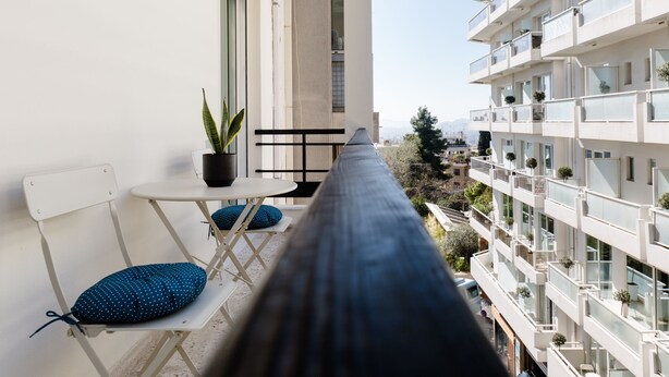 A narrow balcony with a white chair, a small table, and a potted plant. - UPSTREET Desirable 1BD Apt in Kolonaki (Athens)