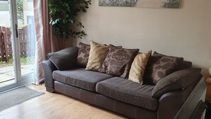 A living room with a sofa, a television, a painting, and a plant. - Cornish Cottage in Hayle near to St Ives (Hayle)