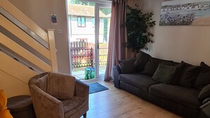 A living room with a wooden floor, a sofa, a chair, and a staircase. - Cornish Cottage in Hayle near to St Ives (Hayle)