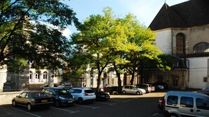 A parking lot with several cars and a building with a pointed roof in the background.