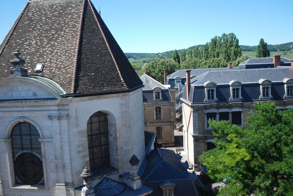 A historical building with a prominent tower and arched windows, surrounded by other structures and trees. - Saint Nicolas Tower in Beaune (Beaune)