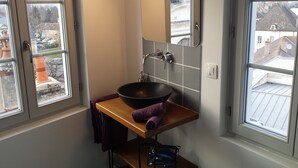 A bathroom with a large window, a sink, a mirror, and a towel rack.