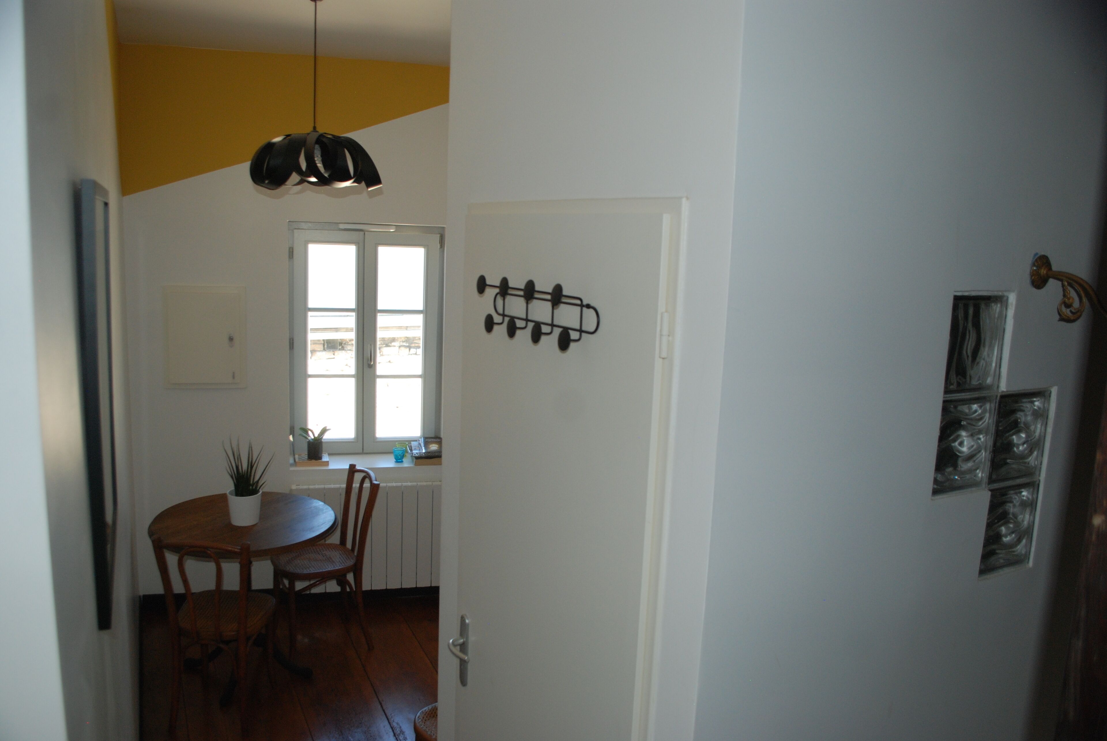 Een eethoek met een houten tafel en stoelen, een hanglamp en een raam met uitzicht.